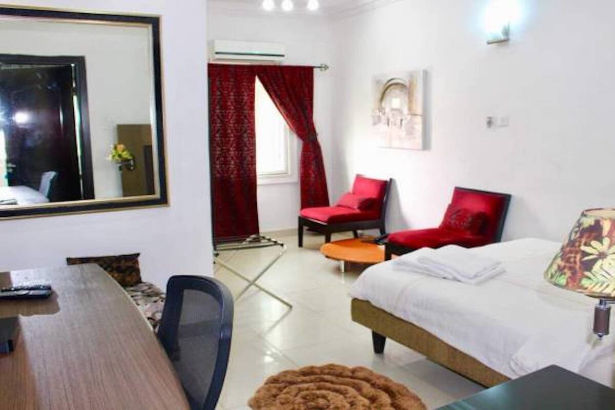 A hotel room with a bed, a desk, a chair, and a mirror.