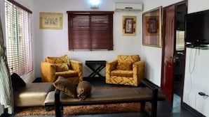 Un salon avec deux fauteuils à motifs, un banc et un canapé.
