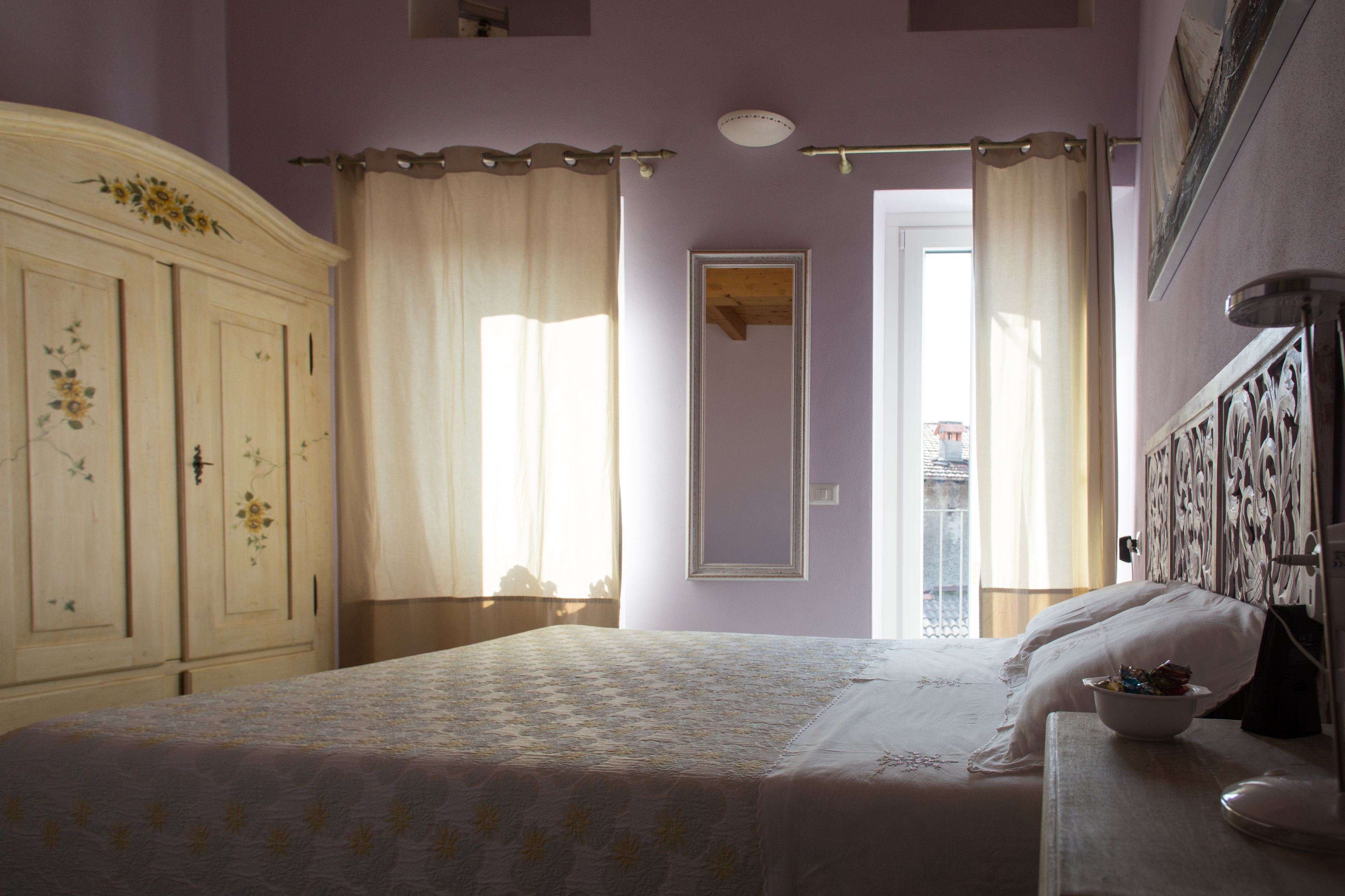Un dormitorio con cama, cómoda, espejo y ventana con cortinas.
