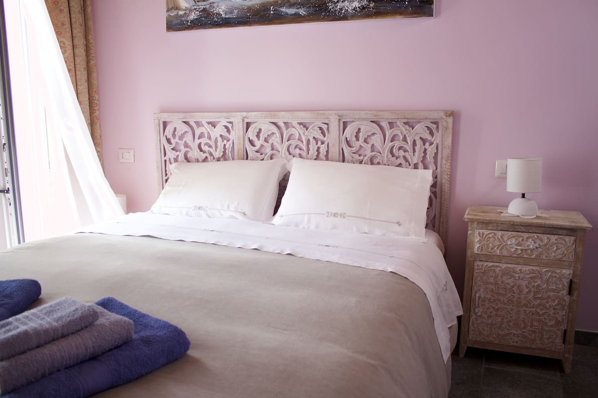 A bedroom with a bed, a nightstand, and a painting on the wall.