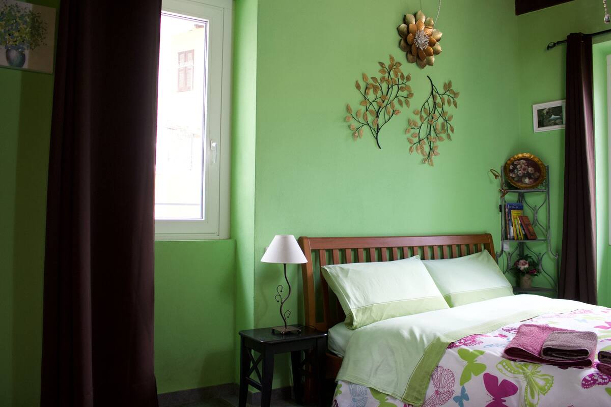 A bedroom with a bed, a nightstand, a lamp, and decorative wall art.