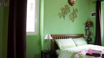 A bedroom with a bed, a nightstand, a lamp, and decorative wall art.