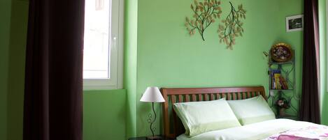 A bedroom with a bed, a nightstand, a lamp, and decorative wall art.
