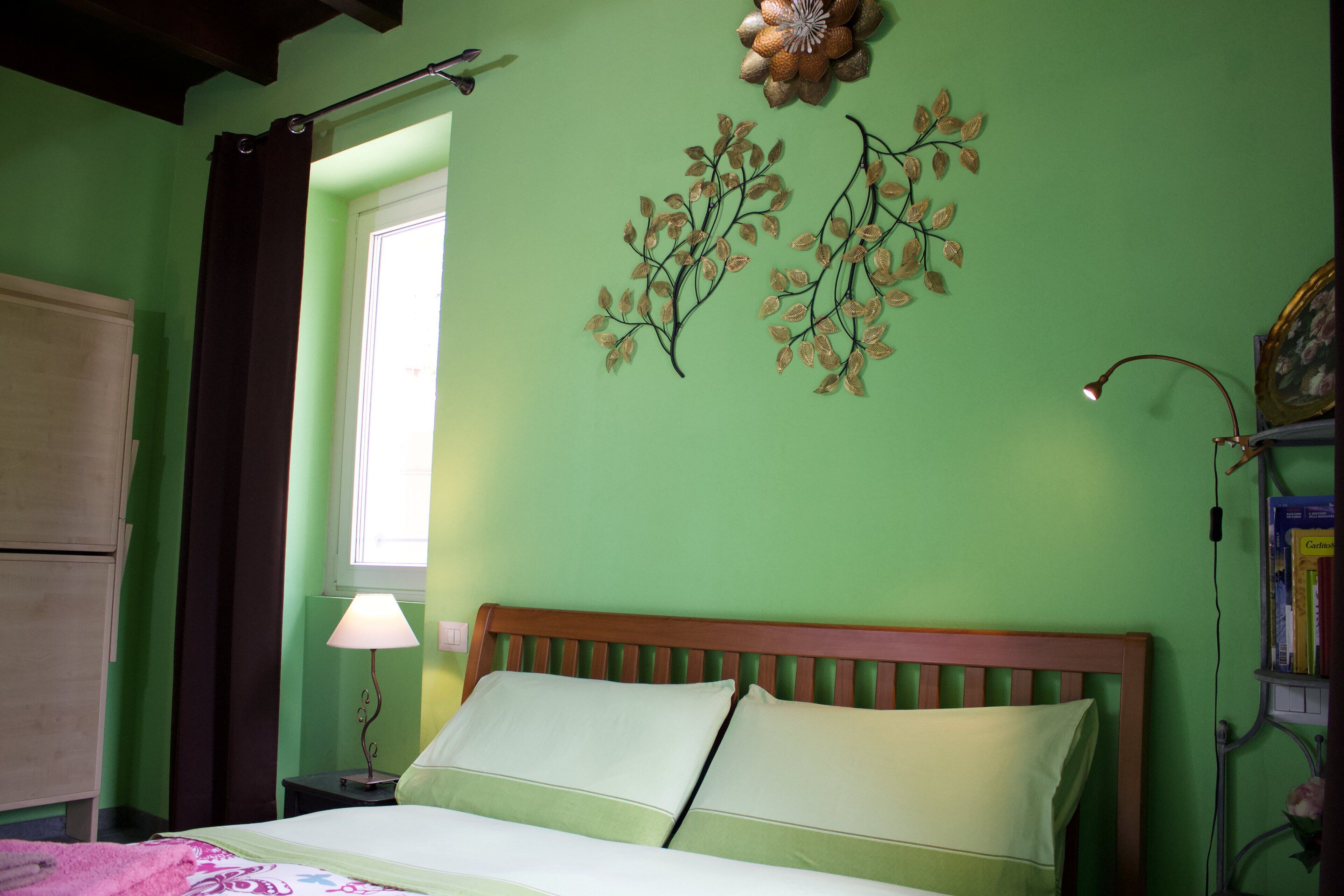 Un dormitorio con cama, ventana, lámpara y adornos en la pared.