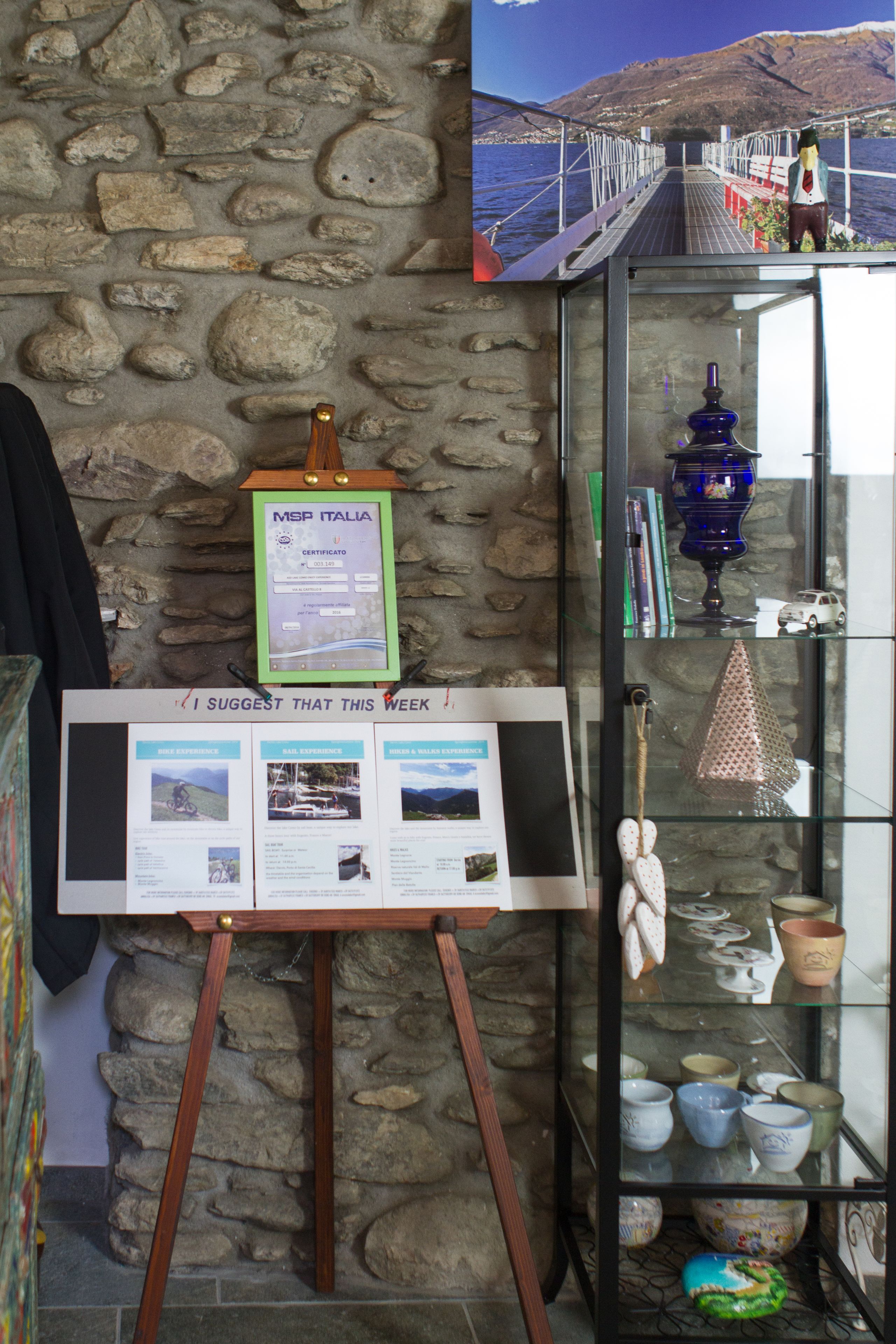 A bulletin board with a certificate, a glass display case with pottery, and a stone wall.