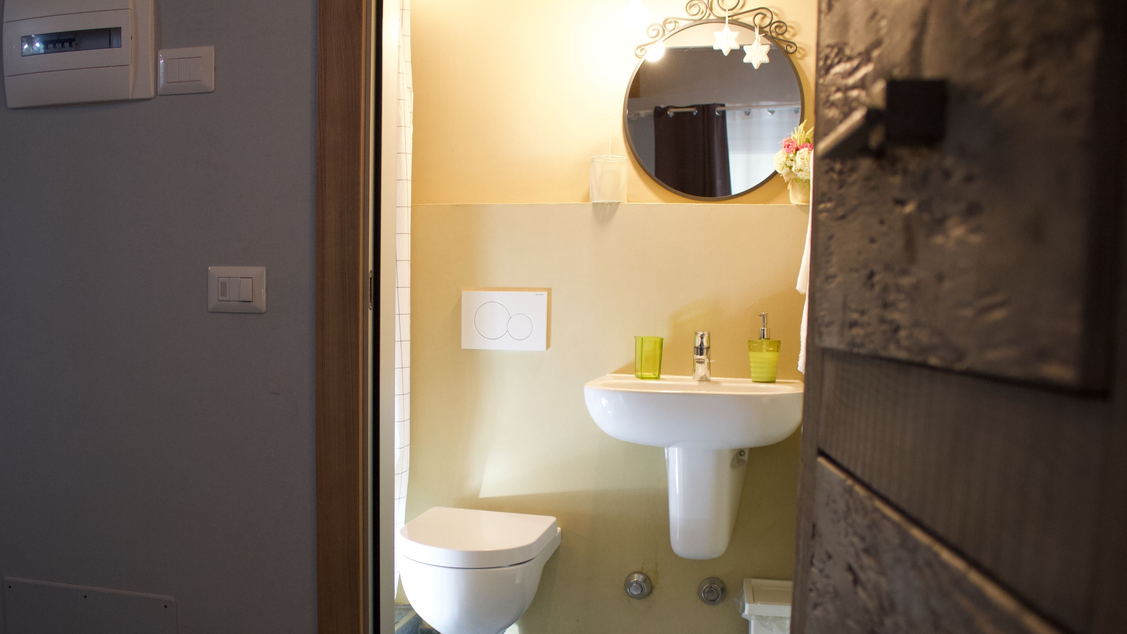 A bathroom with a toilet, sink, and mirror.