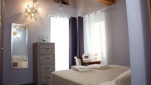 Un dormitorio con cama, cómoda, espejo y ventana con cortinas.