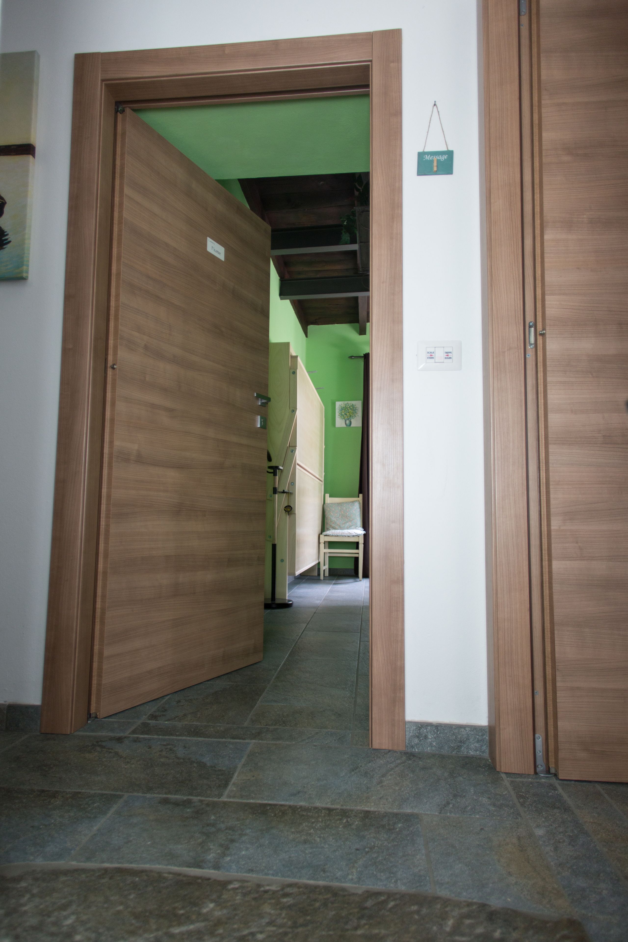 Een gang met houten deuren en een groene wand.