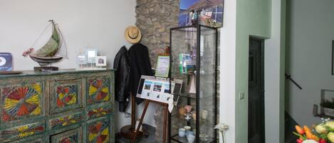 Une pièce avec un mur en pierre, un plafond en bois, une vitrine contenant des objets en céramique et un meuble aux couleurs vives.
