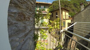 Un muro de piedra, una barandilla metálica y vistas de una zona residencial con casas y vegetación.