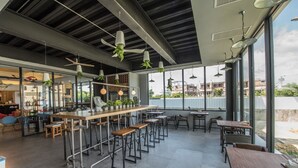 Un intérieur moderne avec un espace bar, de hauts plafonds et de grandes fenêtres offrant une vue sur l’extérieur.