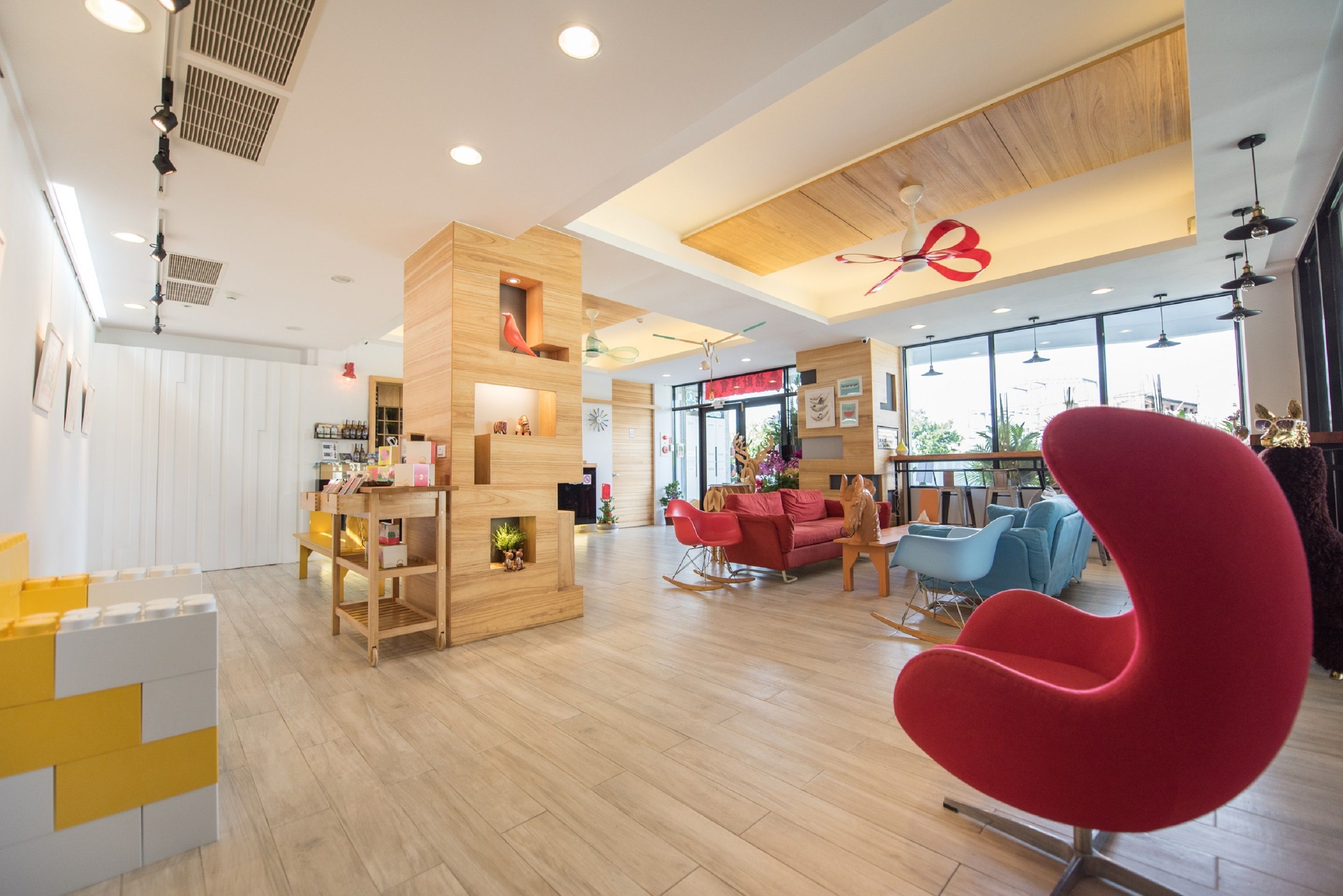 A modern interior with wooden accents, a red chair, and a reception area with a large window.