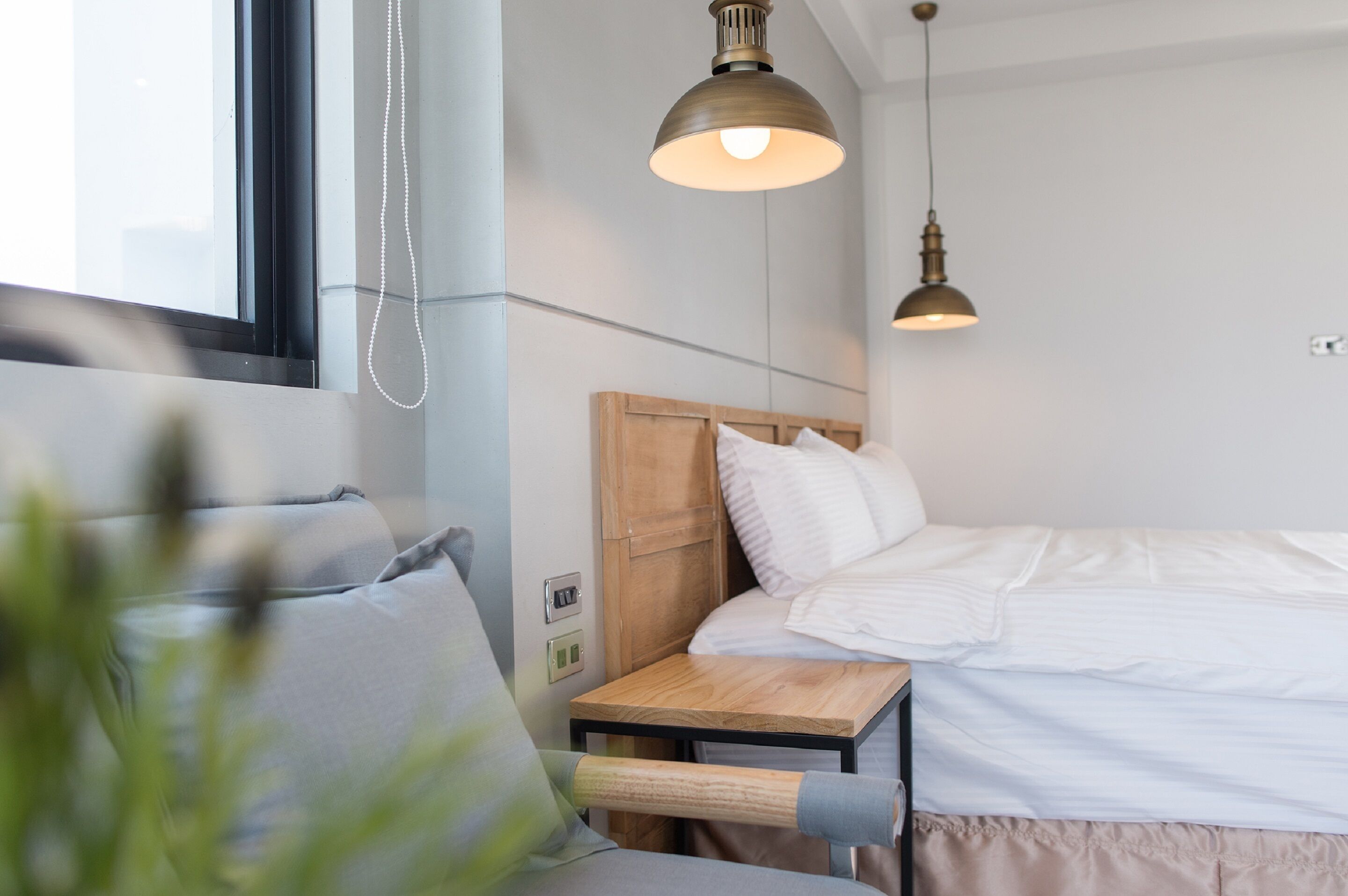 A modern bedroom with a wooden headboard, a bedside table, and a hanging light fixture.