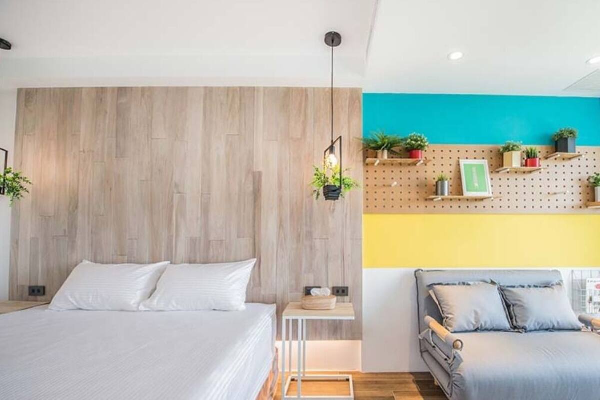 A modern bedroom with a wooden headboard, a bedside table with a lamp, and a bed with white bedding.