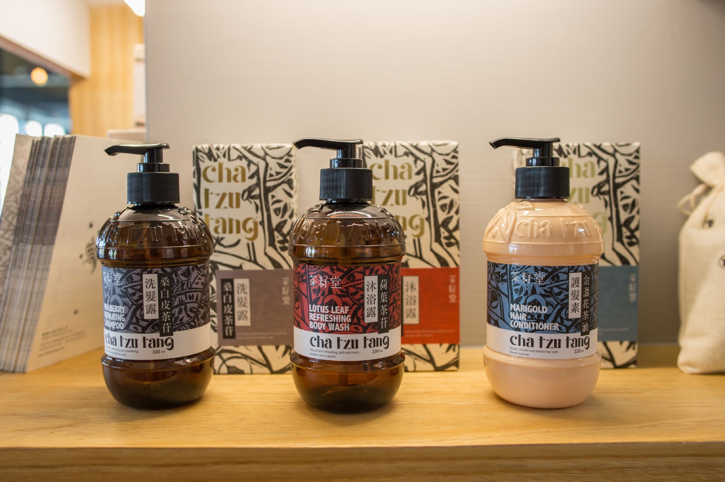 Tres botellas de jabón de baño sobre un estante de madera.