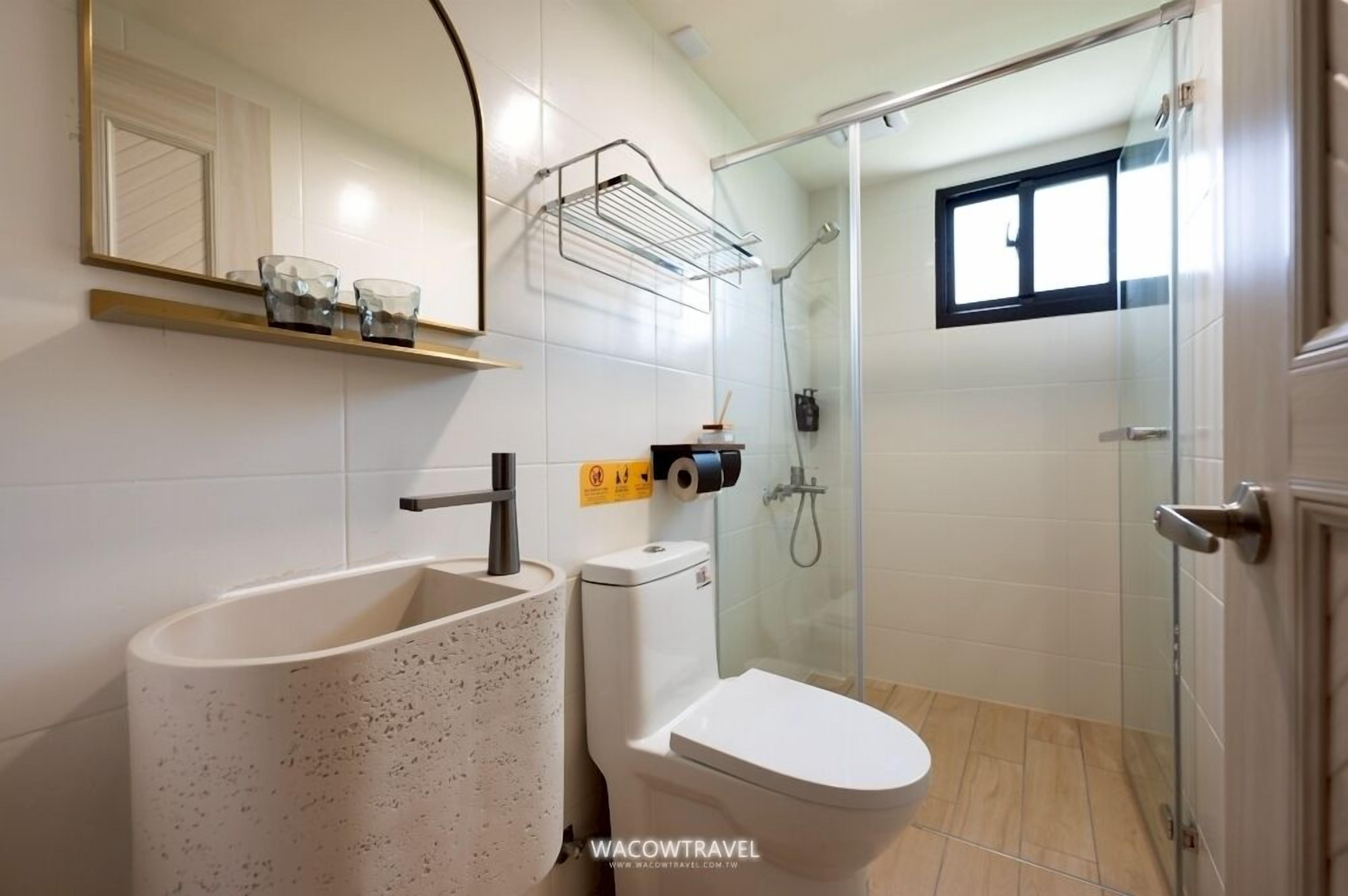 Une salle de bain avec un lavabo sur pied, des toilettes et une douche à parois de verre.