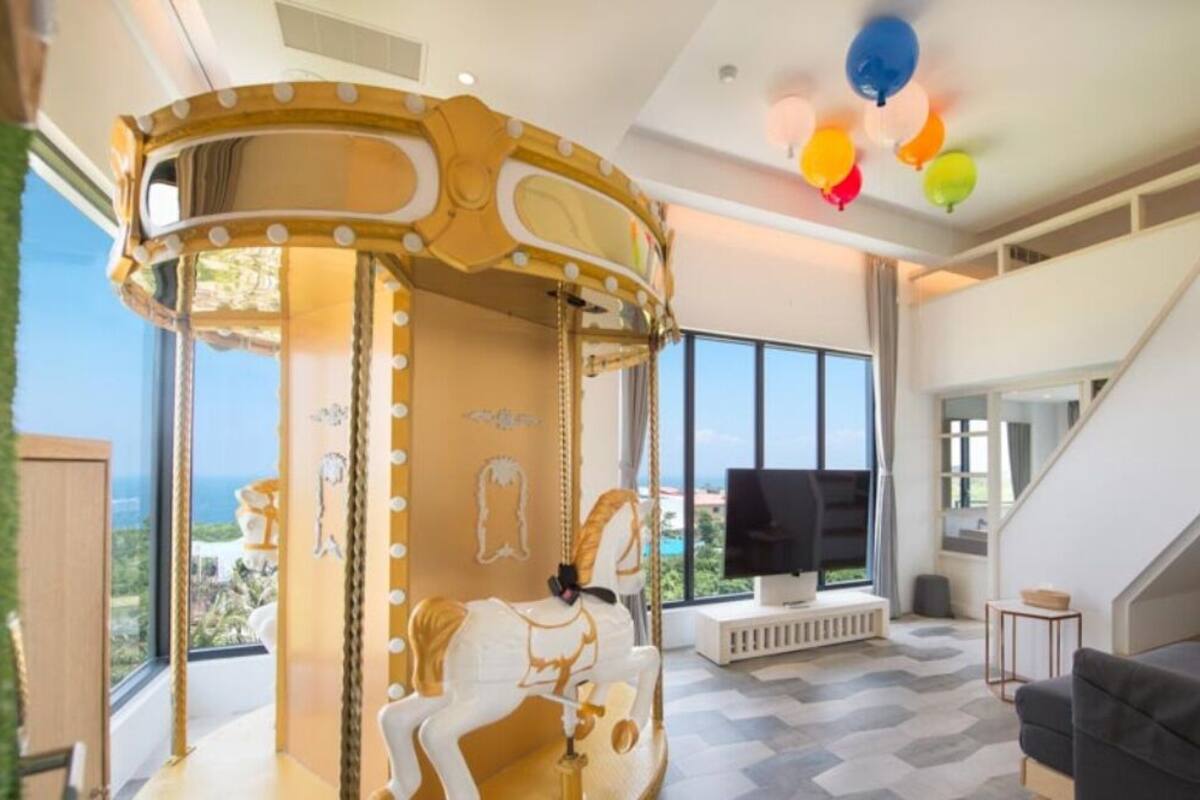 A modern living room with a carousel, large windows, and a flat-screen TV.