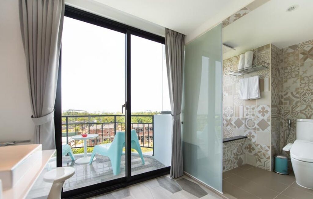 A hotel room with a balcony, a shower area, and a view of the outside.