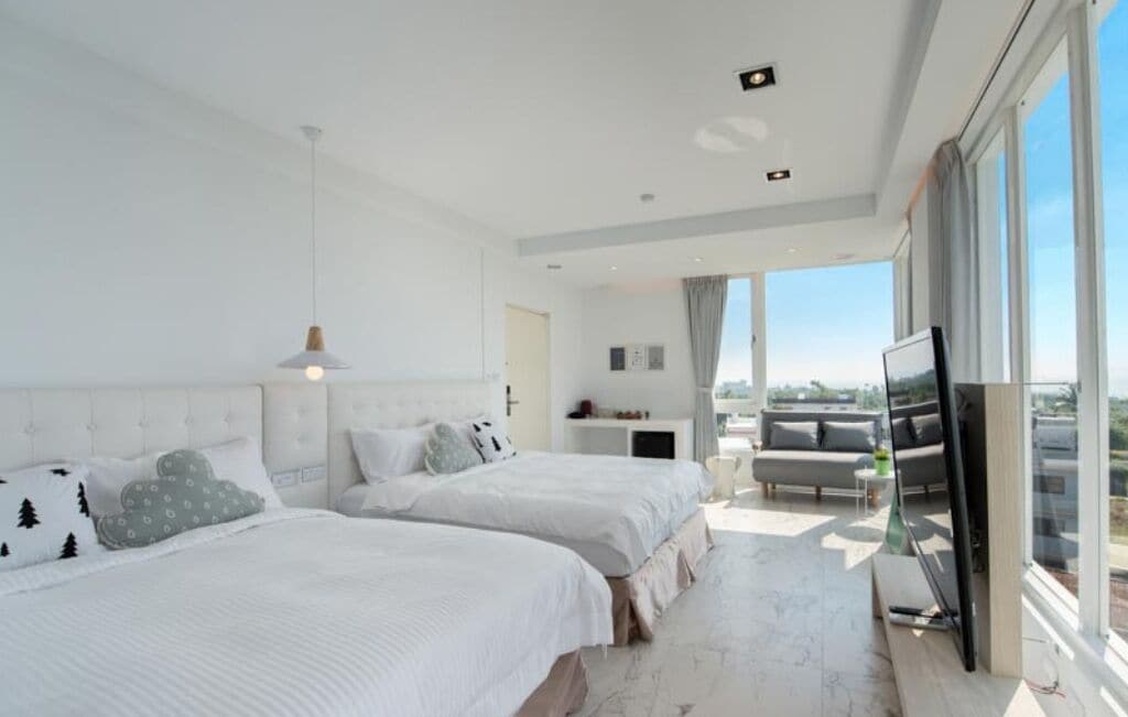 Una habitación de hotel moderna con dos camas, un televisor de pantalla plana y un balcón con vista a la ciudad.