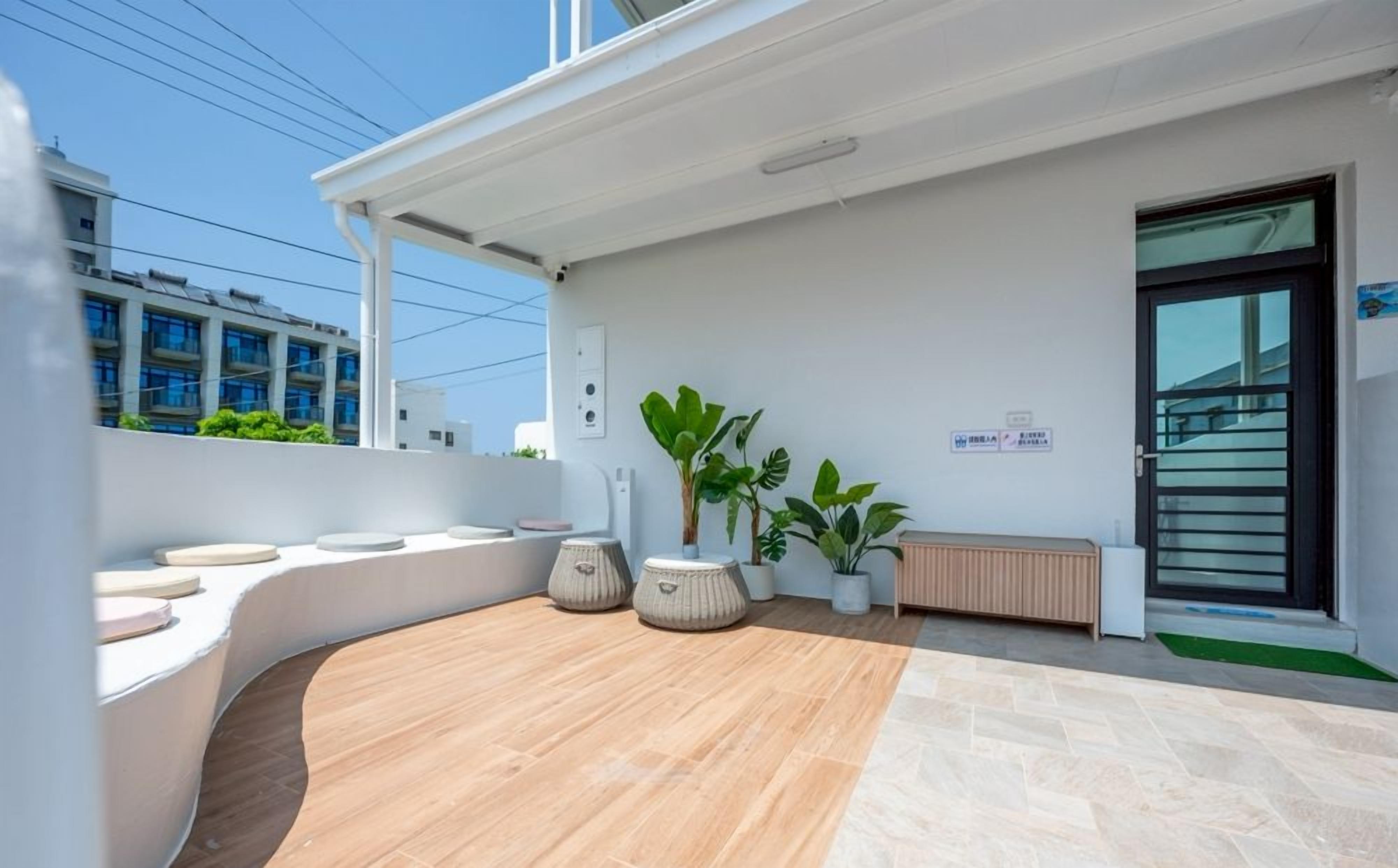 A modern outdoor seating area with a curved bench, potted plants, and a wooden floor.