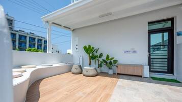 A modern outdoor seating area with a curved bench, potted plants, and a wooden floor.