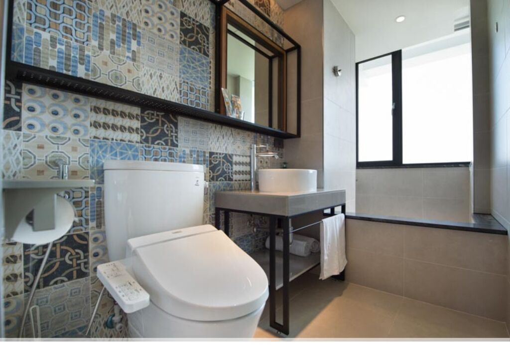 A modern bathroom with a toilet, sink, and a large mirror.
