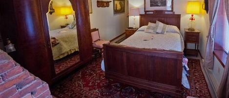 Una camera da letto tradizionale con un letto a baldacchino, uno specchio grande e un tappeto rosso con motivo.