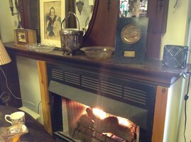 Una chimenea encendida, un reloj y varios objetos decorativos sobre la repisa.