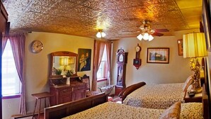 A bedroom with two beds, a dresser, a desk, and a ceiling fan. - Old Winterport Commercial House (Winterport)