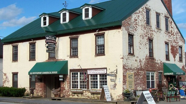 An old building with a green roof, signs for 'Old Winterport Commercial House' and 'Antiques'. - Old Winterport Commercial House (Winterport)