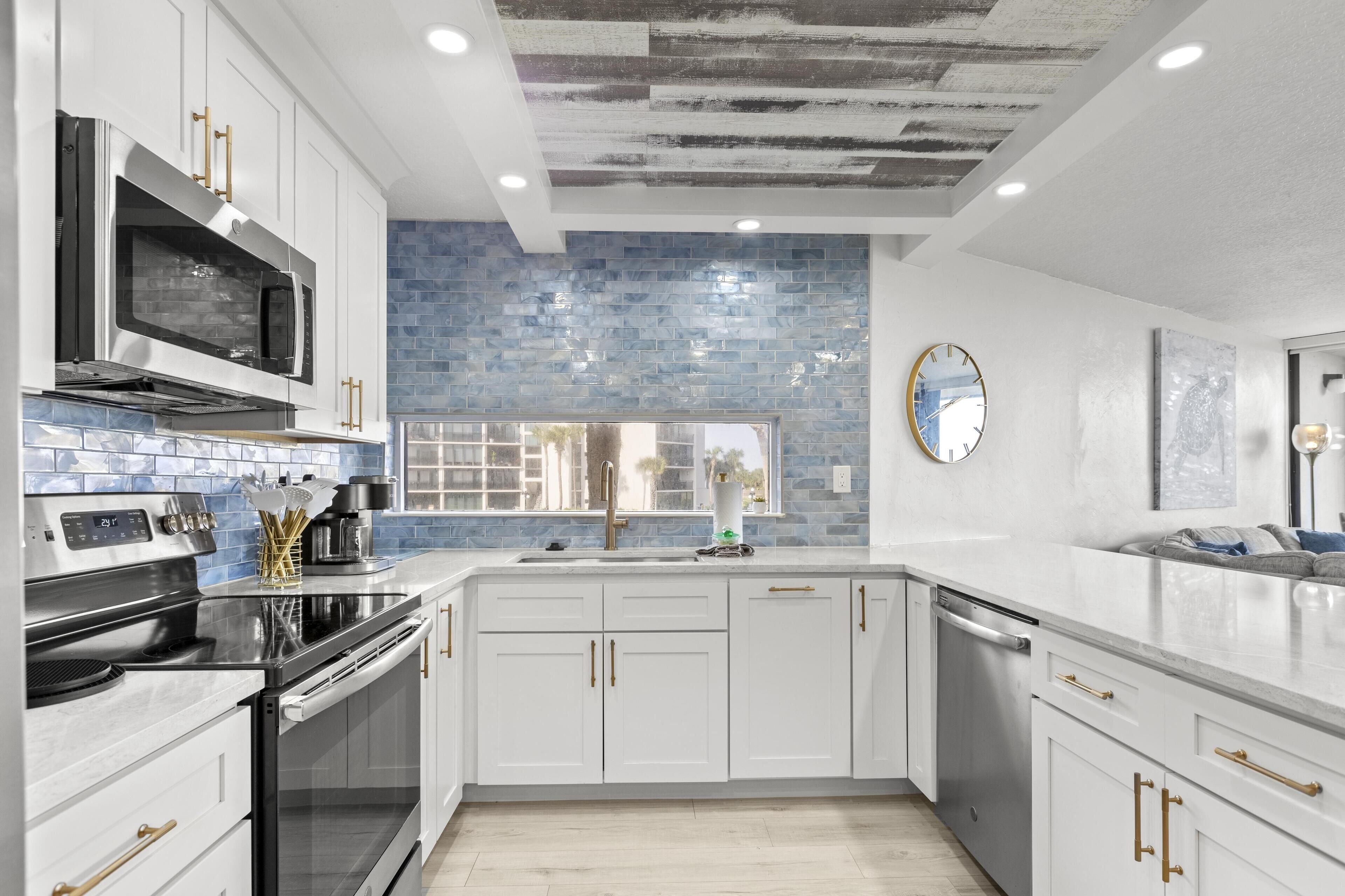 A modern kitchen with white cabinets, stainless steel appliances, and a blue-tiled backsplash.
