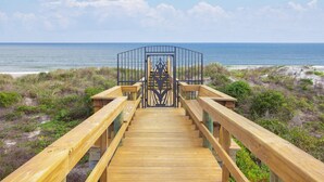 A wooden boardwalk leading to a gate with a metal fence, overlooking a beach and ocean. - **Newly Remodeled 3/2 Oceanfront ~ 3 King Beds!** (Saint Augustine)