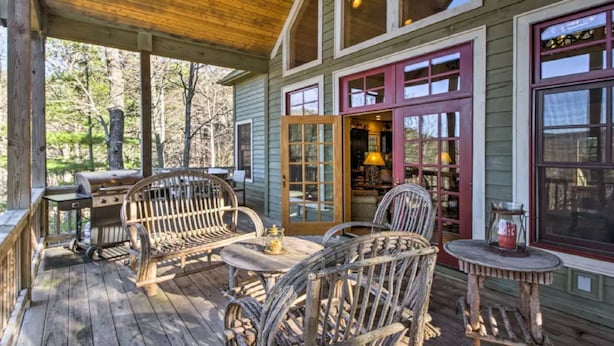 A wooden deck with wicker furniture, a grill, and a small table with a candle.
