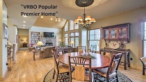 A spacious living room with a large wooden dining table, comfortable seating, and a fireplace.