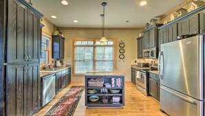 A modern kitchen with dark wooden cabinets, stainless steel appliances, and a central island with a built-in bookshelf.