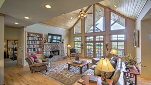 Relax in a spacious living area with a stone fireplace, comfortable seating, and a large bookshelf.