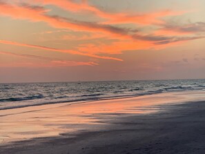 Une plage au coucher du soleil, avec des vagues et une bouée visible au loin.