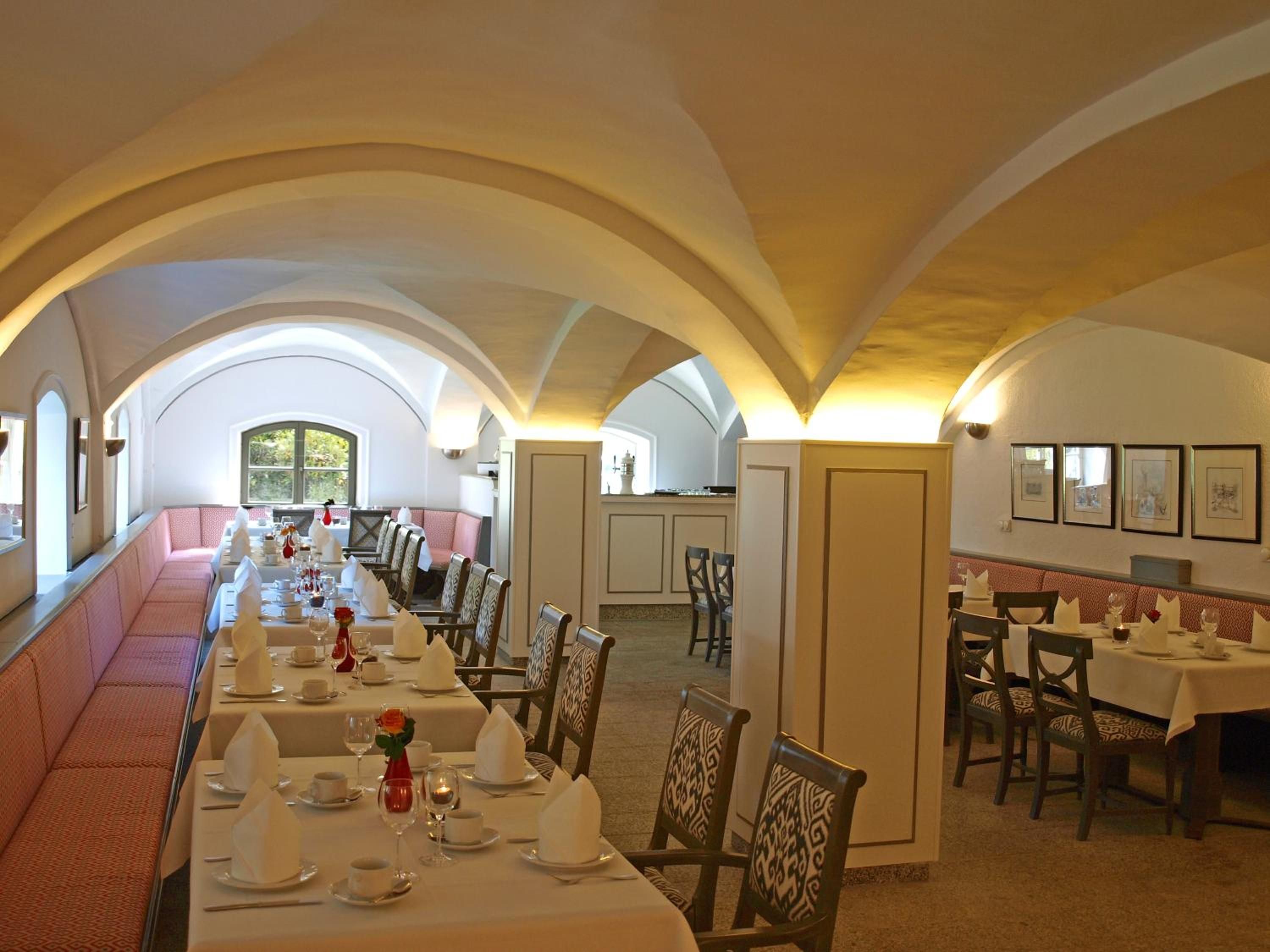 Un comedor con una mesa larga preparada para varios comensales, techos abovedados y vistas al exterior.