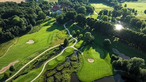 Luchtbeeld van een golfbaan met diverse greens, waterhindernissen en een clubhuis.