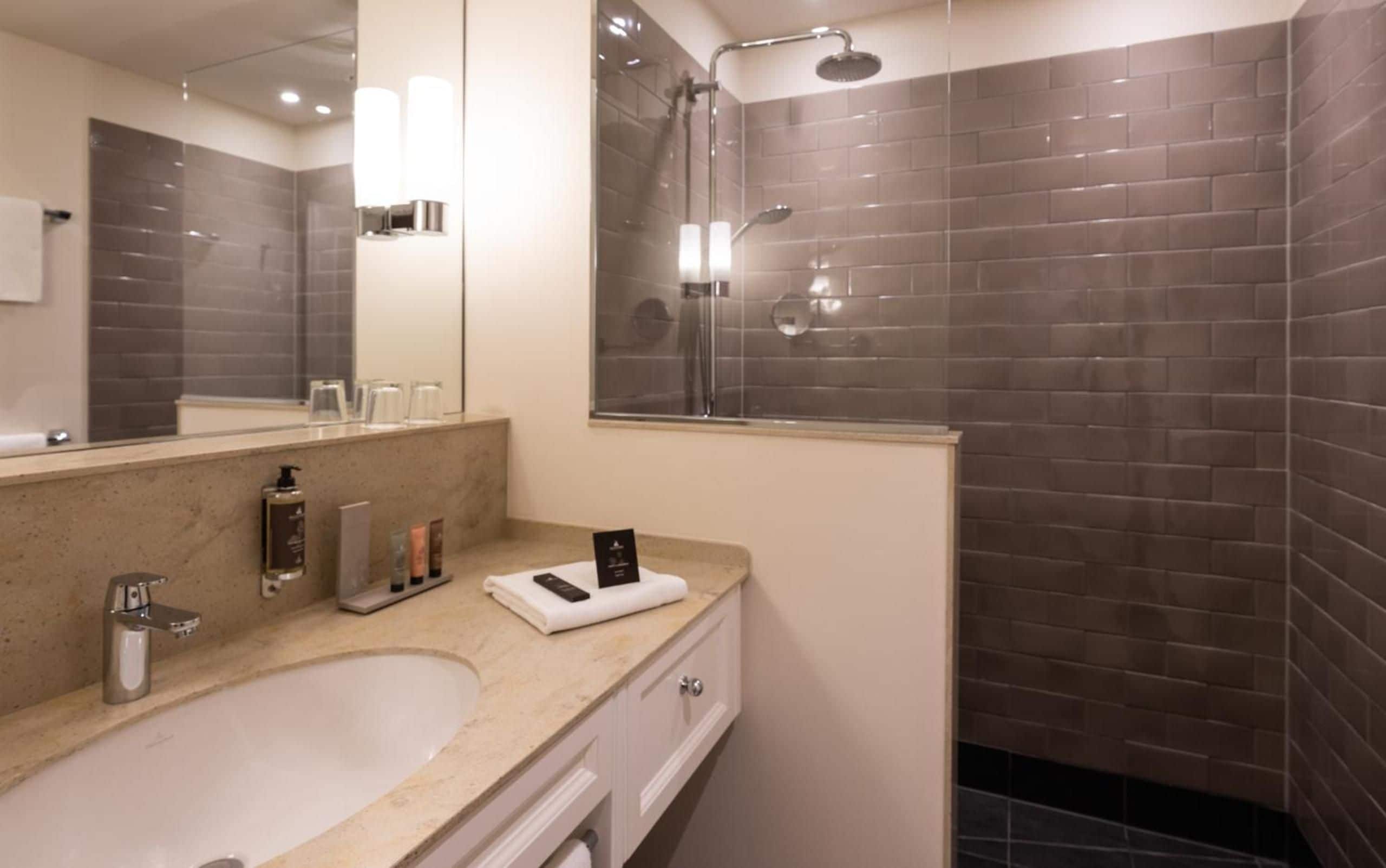 A modern bathroom with a large mirror, a bathtub, and a shower area.