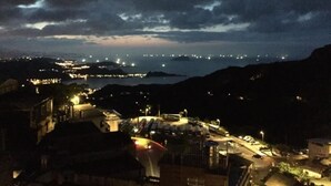 A nighttime view of a coastal town with buildings and a body of water in the distance.
