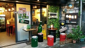 A restaurant with a glass door entrance, a bear statue, and a signboard.