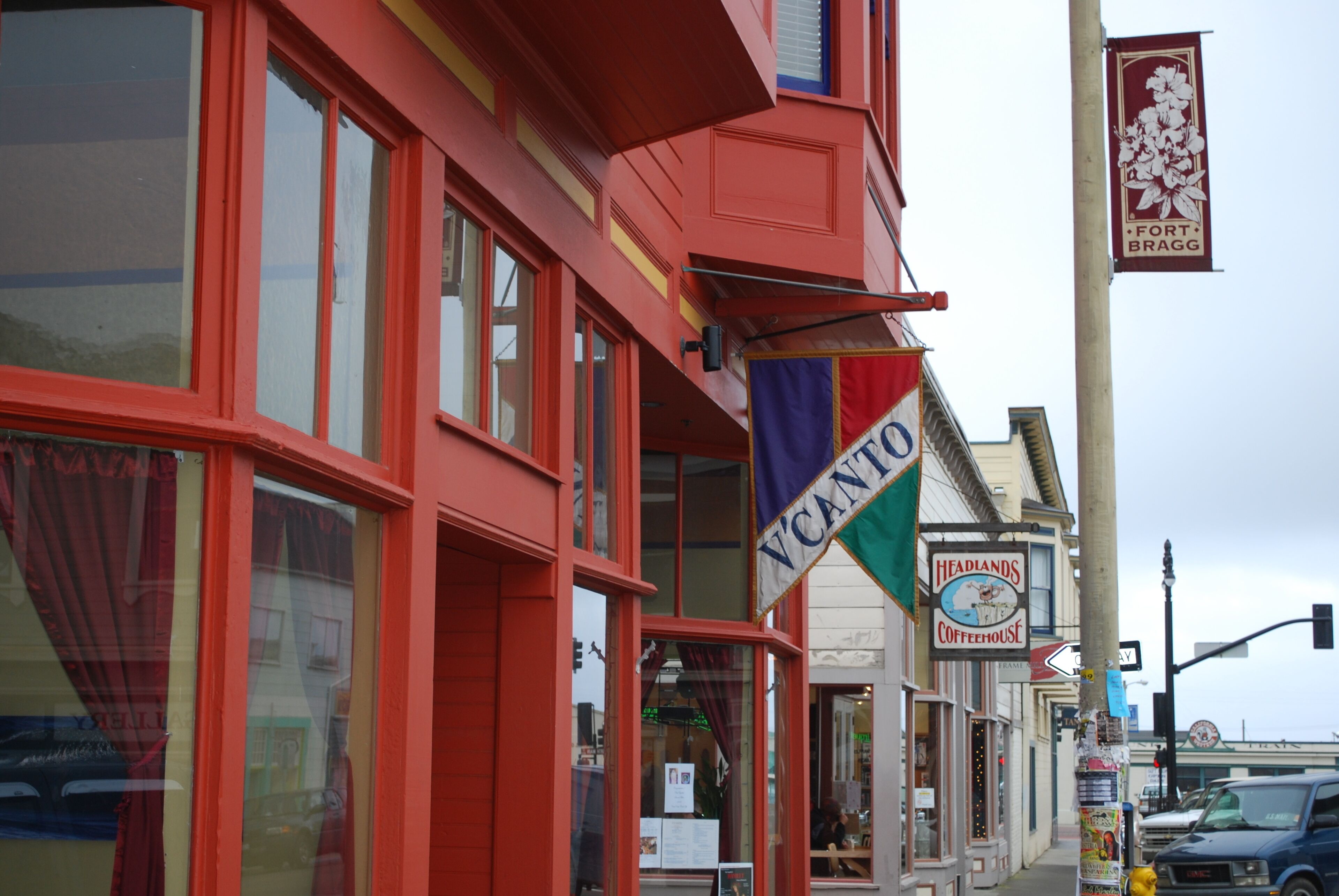 Een rood gebouw met een bord voor 'Headlands Coffeehouse' en een banner met 'Fort Bragg'.