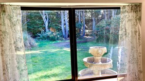A window with a view of a garden and a decorative stone fountain.