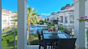 A balcony with a glass table, chairs, and a flower vase. - Sea Heaven Legend Apartments (Fethiye)