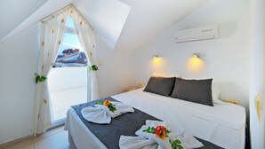 A bedroom with a bed, a window with curtains, and a wall-mounted air conditioner. - Sea Heaven Legend Apartments (Fethiye)