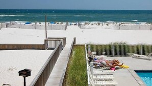 A beachside pool area with a wooden deck leading to the sand, a pool, and lounge chairs. - GULF VILLAGE CONDO LOCATED ON THE BEACH, DIRECT VIEW OF THE GULF, Sleeps 4. (Gulf Shores)