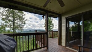 Un terrazzo in legno con vista su montagne e alberi.