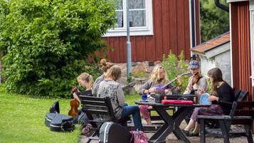 A group of people sitting outdoors with musical instruments, suggesting a casual outdoor music session.