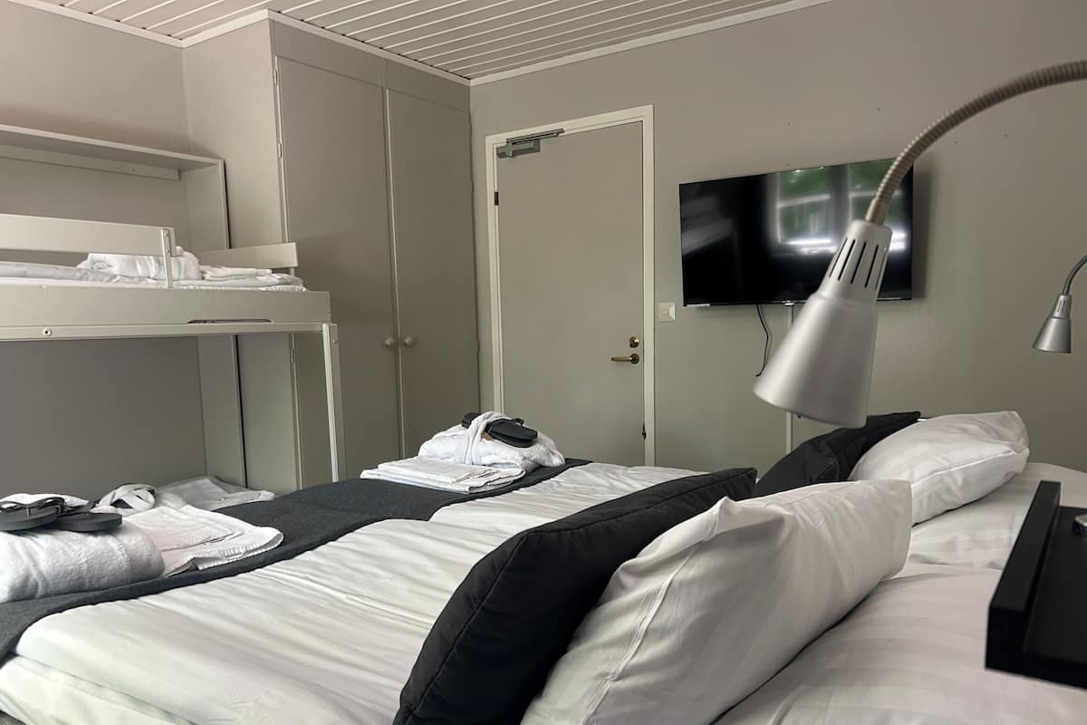 A hotel room with two beds, a TV, a desk, and a wardrobe.